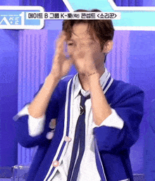 a man in a blue jacket and tie is covering his face