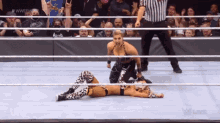 two women are wrestling in a wrestling ring with a referee in the corner