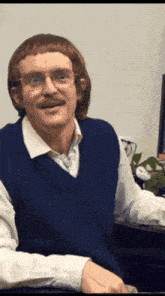 a man with glasses and a mustache is wearing a blue vest and white shirt
