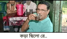 a man is sitting at a table drinking a glass of beer .