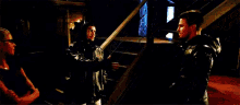 a couple of men are standing next to each other holding swords in a dark room .