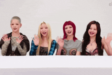 a group of young women are waving their hands and smiling