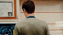 a man is standing in a kitchen looking at a picture of a cat on a white board .