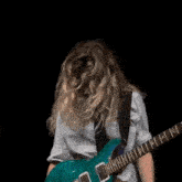 a woman in a white shirt and tie is holding a blue guitar .