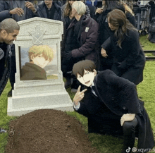 a man kneeling in front of a grave with a picture of a man in it