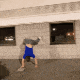 a man in a blue shirt is doing a handstand in front of a brick building