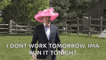 a man wearing a pink hat and a suit is standing in a grassy field .