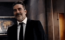 a man in a suit and tie is standing in a room .