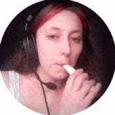 a woman wearing headphones and a microphone is blowing a white item into her mouth