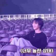 a man is sitting in a row of purple chairs in an auditorium .