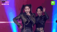 two women are dancing on a stage with a microphone in their hand .