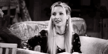 a woman is sitting on a couch in a black and white photo and smiling .