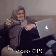 a woman is sitting on a couch with an apple laptop and a cigarette in her hand