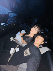 a boy and a girl laying on a couch in a movie theater