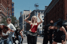 a woman in a red top is dancing in front of a building that has the word palace on it
