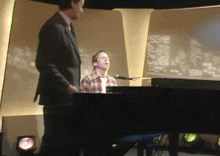 a man singing into a microphone while another man stands behind him