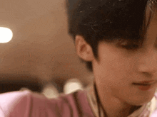 a close up of a person 's face with a pink shirt on and headphones on .