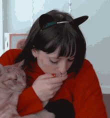 a woman with cat ears on her head holds a cat