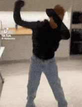 a man is dancing in a kitchen with his hands in the air .