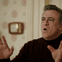 a man in a maroon sweater is making a funny face with his hands outstretched
