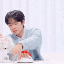 a young man in a blue sweater is ironing a piece of fabric .