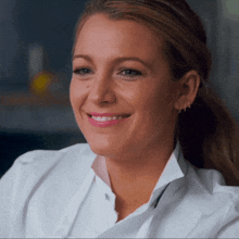 a woman wearing a white shirt and hoop earrings smiles for the camera