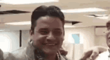 a man is smiling and looking at the camera while standing next to another man .