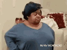 a woman wearing a blue shirt is standing in a living room .