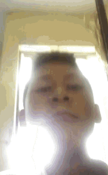 a blurry picture of a person 's face with a window behind them