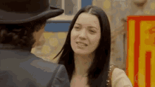 a man and a woman are standing next to each other and the woman is wearing a hat .
