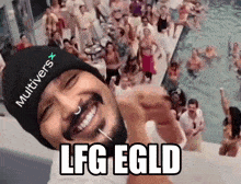 a man wearing a beanie that says multiverse is smiling in front of a pool full of people