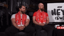 two men sitting in front of a sign that says hey ( ew )