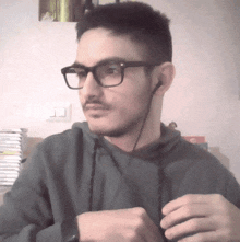 a man wearing glasses and ear buds looks to the side