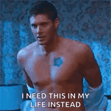 a shirtless man is standing in a bed with his hands on his hips and a tattoo on his chest .