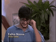 a man wearing glasses and a blue shirt with the name falha nossa vira-lata written on the bottom