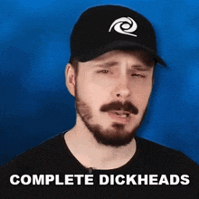a man with a beard is wearing a hat that says complete dickheads on it .