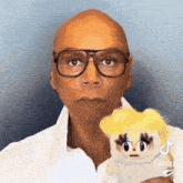 a bald man wearing glasses is holding a stuffed animal doll .