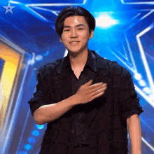 a man stands on a stage with his hand on his chest and a star in the background