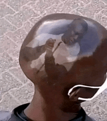 a man 's head with a reflection of a man in it .