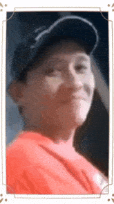 a man wearing a hat and a red shirt is looking at the camera