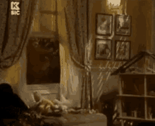 a person is laying on a bed in a room with pictures on the wall and a window .