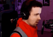 a man wearing headphones and a red shirt is sitting in front of a microphone .
