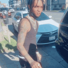 a man wearing a black tank top has a california license plate that says zvl8077