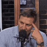 a man in a blue shirt is sitting in front of a microphone