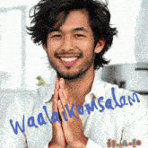 a man with his hands folded in front of a sign that says waalakum salam