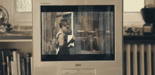a woman in a black dress is standing in front of a flatron tv