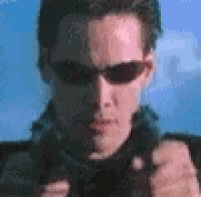 a man wearing sunglasses is holding a gun .