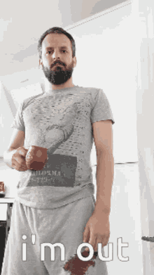 a man with a beard is holding a cup of coffee and says i 'm out on the bottom