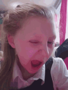 a little girl is making a funny face with her mouth open and her eyes closed .