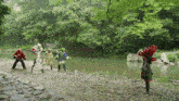 a group of people in costumes are standing on a rocky shoreline near a river